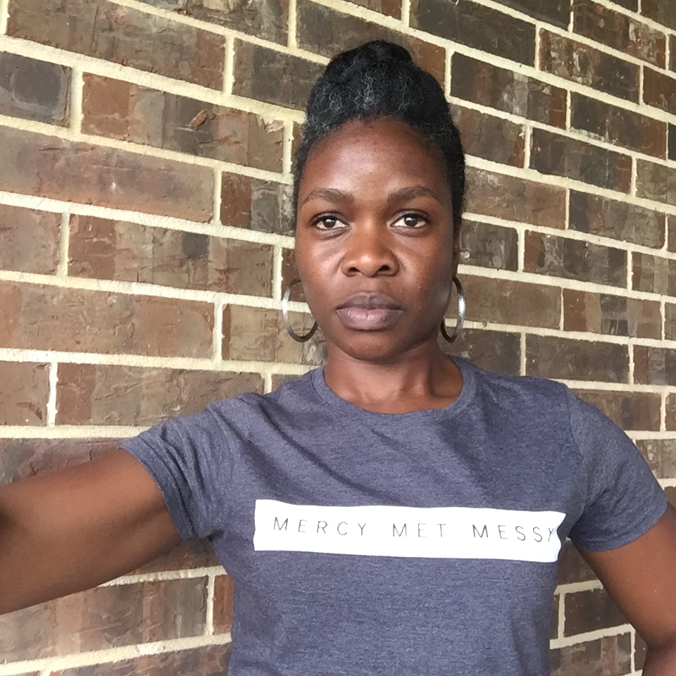 Vanessa A. Harris modeling her Mercy Met Messy tshirt design.